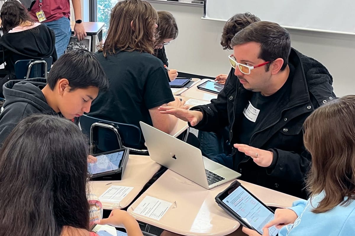 Photo of a Classkick engineer working with students at a cluster of desks